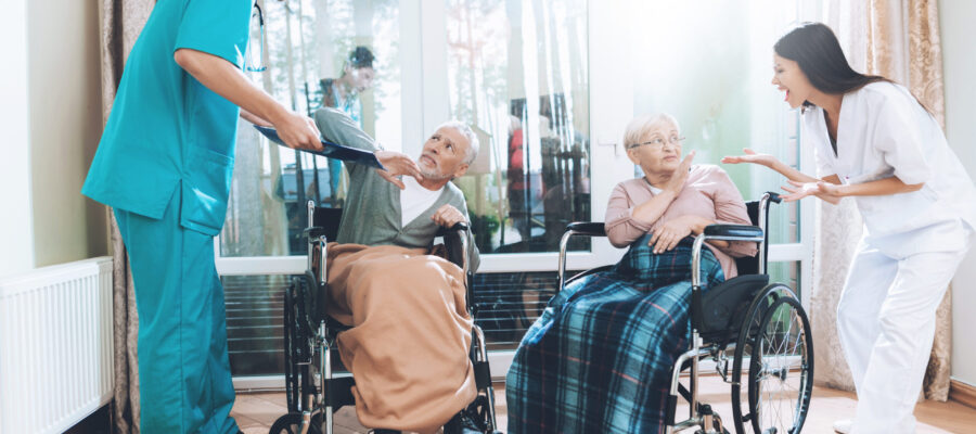 Medical workers argue with an elderly couple in a nursing home. They are very emotional. The elderly are very frightened. They are sitting in a wheelchair.