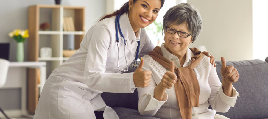 Recommended professional medical service for elderly people, age medicine concept. Happy smiling hispanic female doctor and old lady patient gesturing thumbs up to camera showing satisfaction emotion